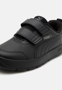 Chaussure de sport noire en cuir synthétique, dotée de deux bandes auto-agrippantes, d'une finition texturée et d'un logo sur le côté.