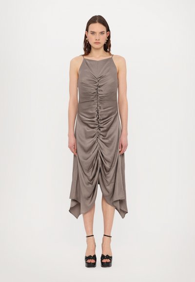 Ruched gray dress with a straight neckline and asymmetrical hem, made from a smooth fabric. Worn with black platform shoes.