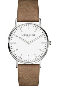 Montre ronde avec un cadran blanc, un boîtier en argent et un bracelet en cuir marron. Présente des index horaires minimalistes et un logo de marque subtil.