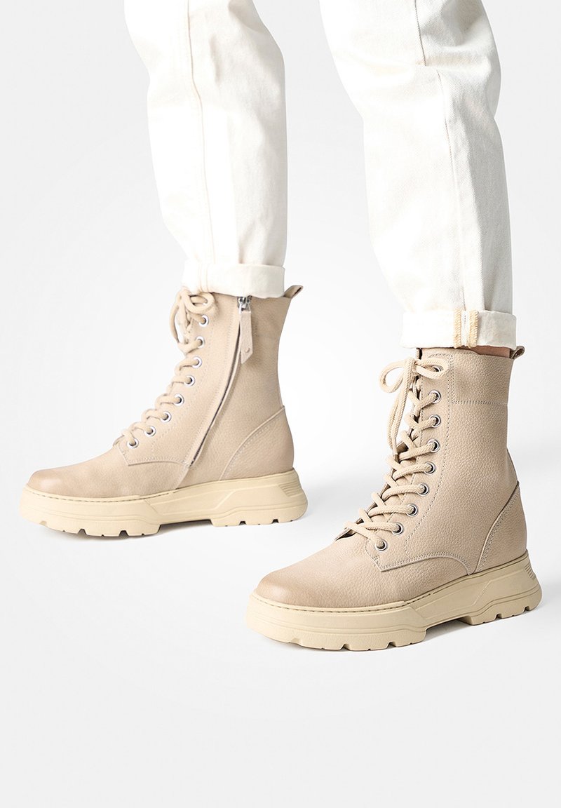 Beige Schnür-Stiefel im Combat-Stil mit strukturiertem Lederoberteil und Gummisohle, ausgestattet mit einem seitlichen Reißverschluss und einem klobigen Design.