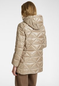Beige, gewatteerde pufferjack met een capuchon, met een glanzende, soepele textuur en een ruitpatroon. Het jack komt tot halverwege de dijen en heeft lange mouwen.
