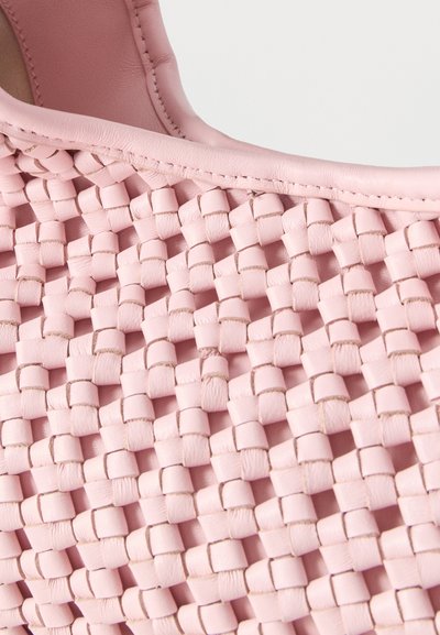 Κοντινό πλάνο ροζ υφής πλεγμένου δέρματος με ραμμένη δερμάτινη επένδυση σε ένα αξεσουάρ μόδας.