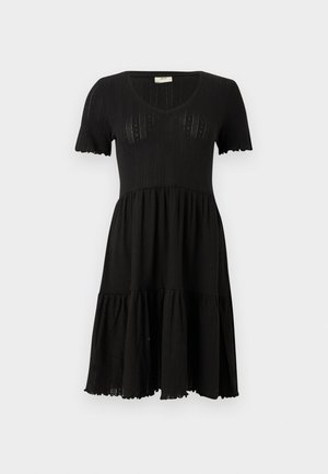 Svart stickad klänning med V-ringning, korta ärmar och lager-på-lager kjol. Har ribbad textur och scallopade ärmslut.