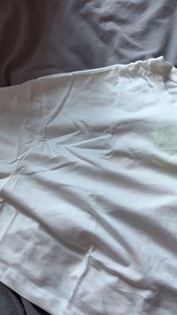Valge puuvillane T-särk, väljapandud tasapinnale. Sellel on lühikesed varrukad, ümmargune dekoltee ning nähtavad voldid. Mustreid ega graafikat ei ole.