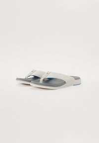 Grå og hvite flip-flop sandaler med en teksturert stropp, myk såle og et minimalistisk design, med en blå akcent på sålen.