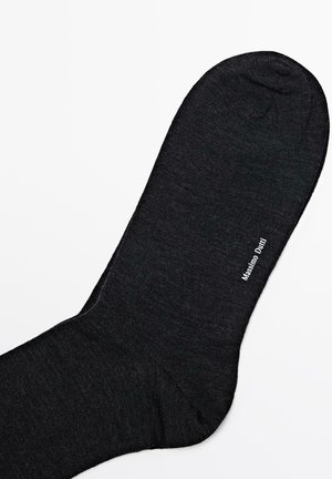 Schwarze Socke aus einem strukturierten Material, mit einer abgerundeten Spitze und dem Logo "Massimo Dutti" in Weiß auf der Seite bedruckt.