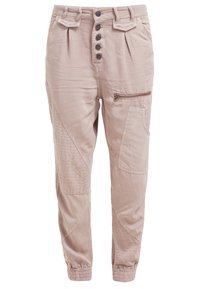 Pantalon décontracté beige clair avec devant boutonné, poignets élastiques, multiples poches dont des styles zippées et à rabat, et détails de panneaux cousus.