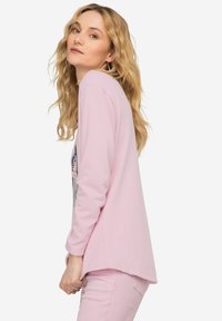 Langsleeve roze top met een ronde hals, voorzien van een grafisch ontwerp aan de voorkant. Zachte katoenmateriaal met een losse pasvorm en een gebogen zoom.