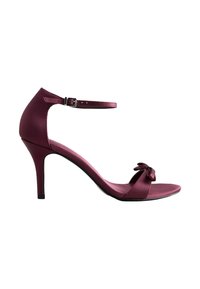 Sandalia de tacón de satén burdeos con una delicada correa en el tobillo, punta abierta y un detalle decorativo de lazo en la parte frontal. Textura suave, diseño elegante.