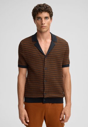 Camicetta a maniche corte con pattern a righe in arancione e blu navy. Presenta un colletto a contrasto, tessuto testurizzato e un design aderente.