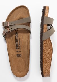 Birkenstock sandal i jordnær grøn med to justerbare stropper med kobber spænder, kork sål og en tekstureret brun bund. Størrelse 38.