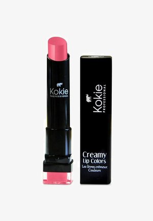 Kokie Professional Creamy Lip Color valkoisessa sylinterimäisessä putkessa, jossa on litteä pää vaaleanpunaisesta huulipunasta. Mukana on myös yhteensopiva musta laatikko, jossa valkoista tekstiä.