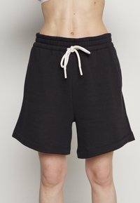 Svarta bomullsblandade shorts med en mjuk textur, resårmidja och vit dragsnöre. Har en avslappnad passform och en längd upp till mitten av låret.
