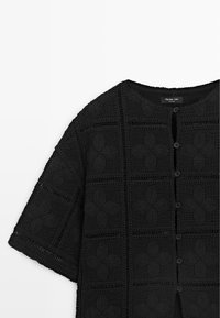 Czarny krótki sweterek na szydełku z krótkim rękawem, z kwiatowymi wzorami i guzikami z przodu, oznaczony jako Massimo Dutti, wyświetlony na płasko na białym tle.