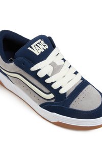 Vans spordijalatsid, millel on tumesinine ja hall nahkpehme ülemine osa, valged paelad ja tekstureeritud kummist tallad, millel on perforatsioonid.