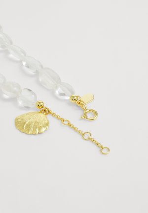 Transparante kralenhalsketting met een gouden kettingsluiting en een gestructureerde gouden schelp bedel op een witte achtergrond.