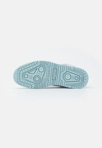 Semelle d'une basket Puma bleu clair avec des motifs de bande de roulement circulaires et linéaires et le logo Puma au centre.