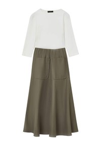 Top bianco a maniche lunghe abbinato a una gonna verde oliva con forma svasata e due grandi tasche frontali. Texture liscia, design casual.