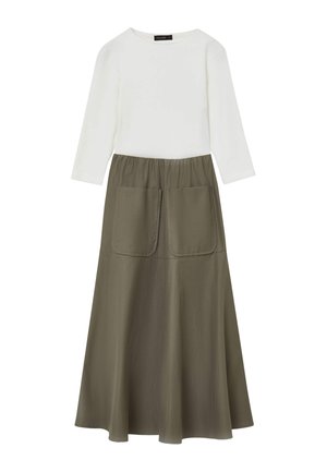 Top bianco a maniche lunghe abbinato a una gonna verde oliva con forma svasata e due grandi tasche frontali. Texture liscia, design casual.