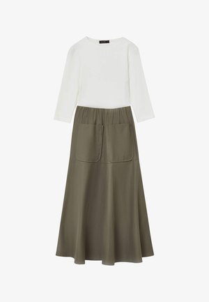 Weißes Langarmoberteil kombiniert mit einem olivgrünen Rock in ausgestellter Form und zwei großen frontalen Taschen. Glatte Textur, lässiges Design.