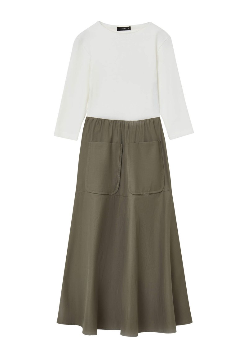 Top bianco a maniche lunghe abbinato a una gonna verde oliva con forma svasata e due grandi tasche frontali. Texture liscia, design casual.