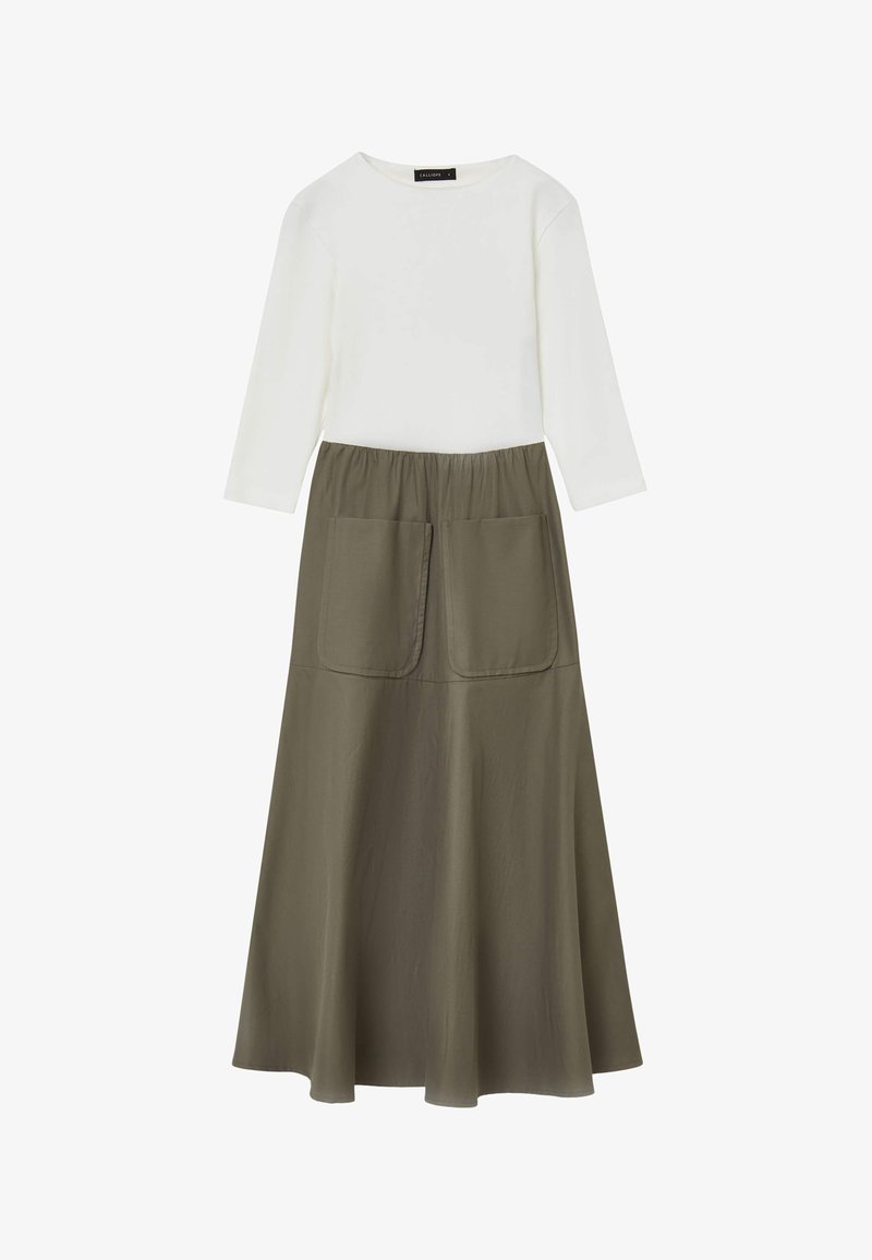 Top bianco a maniche lunghe abbinato a una gonna verde oliva con forma svasata e due grandi tasche frontali. Texture liscia, design casual.