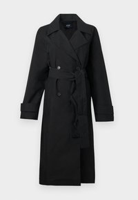 Melns tranšejas mētelis no gludas materiāla, ar dubultpogātu priekšpusi, lieliem atloki, jostu viduklī un aprocēs reizēm.