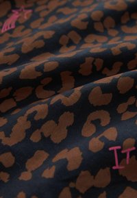 Tessuto con stampa leopardata in marrone e nero con una texture liscia. Presenta del testo ricamato rosa sul motivo.