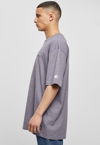 Grey cotton t-shirt with a loose fit, featuring short sleeves and a small logo on the chest. Smooth texture with a slight stretch.