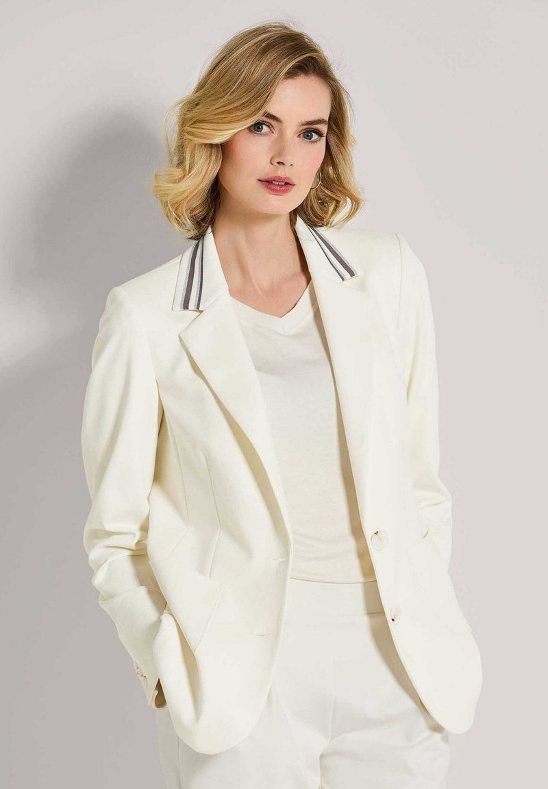 Witte blazer met grijs gestreepte kraag, slim fit, enkelvoudig geknoopt ontwerp en twee voorkeurszakken, gecombineerd met een licht crèmekleurig top.