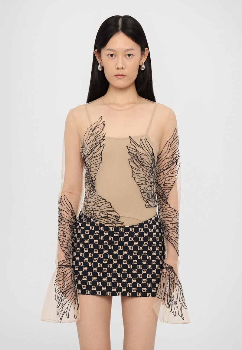 Top in rete nudo con maniche lunghe trasparenti e ricami neri a forma di ali; abbinato a una mini gonna pattern in blu navy e beige.