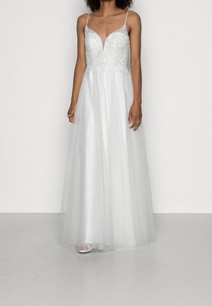 Robe de mariée blanche avec un décolleté en V profond, des perles délicates sur le corsage et une jupe fluide en tulle. Bretelles spaghetti ajustables.