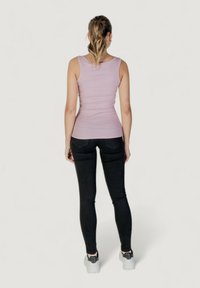 Top aderente rosa chiaro con texture a coste, abbinato a jeans neri slim-fit. Cuciture visibili e design minimalista.