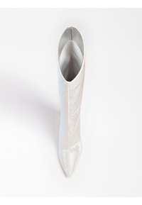 Silver ankle boot featuring a sleek, pointed toe and textured surface with a shimmering effect. Interior lined in smooth material.