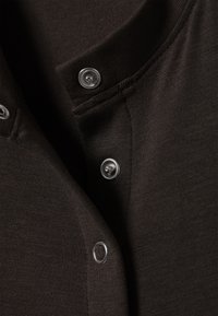 Brun, bomullsblandingstoff med en teksturert overflate; har sølvknapper ved kragen og skulderen; klassisk skjortedesign.