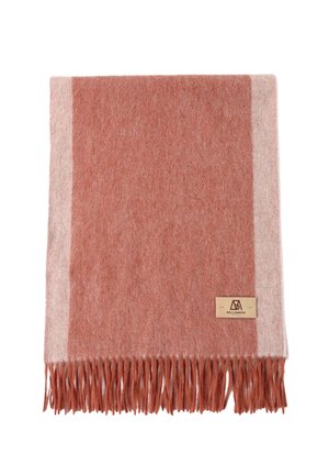 Coperta in morbida lana con un design rosso ruggine e beige chiaro, con un bordo frangiato e una piccola etichetta in pelle. Lavabile in lavatrice.