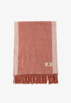 Soft wool blanket featuring a rust red and light beige design, with a fringed edge and a small leather label. Machine washable.