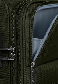 Valigia verde oliva con tessuto testurizzato, diverse cerniere e una fodera interna azzurra. Presenta accessori in metallo e un'etichetta con il logo.