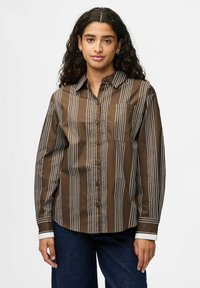 Camicia a righe marroni con bottoni e maniche lunghe, caratterizzata da righe verticali bianche e una tasca sul petto; texture liscia e colletto standard.