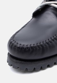 Μαύρο δερμάτινο παπούτσι με στρογγυλεμένη μύτη, λεπτομερή ραφή κατά μήκος της ραφής και υφασμένη λάστιχη σόλα με ανθεκτικό πρότυπο πέλματος.