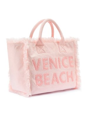 Pink fabric tote bag with plush fringe trim and embroidered "VENICE BEACH" text. Features dual fabric carry handles.