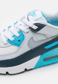 Sneaker Nike Air Max con tomaia grigia e blu navy, dettagli azzurri, lacci bianchi e un'unità air visibile nella suola.