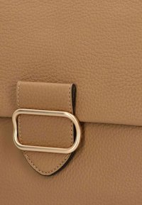 Beige strukturiertete Ledertasche mit einem rechteckigen Deckel, der mit einem goldenen Metallakzent und einer gestickten Detailverzierung entlang der Kanten versehen ist.