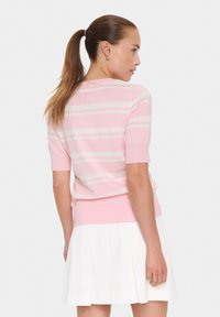 Suéter de punto a rayas rosa con mangas cortas, cuello y dobladillo acanalados, combinado con una falda plisada blanca. Textura suave y apariencia blanda.