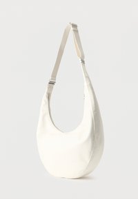 Λευκή τσάντα ώμου σε σχήμα ημισελήνου με ρυθμιζόμενο λουρί και ορατό φερμουάρ στο πλάι, τοποθετημένη πάνω σε απλό ανοιχτό φόντο.