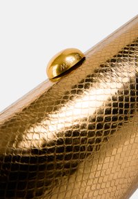 Gold snake-patterned clutch with a shiny finish. Features a rounded gold clasp with "Marc Cain" embossed on it. Sleek, elongated shape.