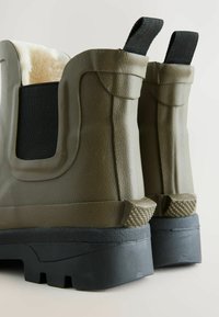 Khaki rubberen laarzen met een gestructureerde afwerking, zachte binnenvoering, elastische zijpanelen en zwarte rubberen zolen met profielpatronen.