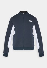 Námornícky modrá zipsová bunda s bielymi bočnými panelmi, rebrovanými manžetami a malou značkovou nálepkou na hrudi. Vyrobená z hladkej, ľahkej tkaniny.