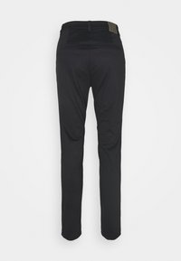 Pantalon noir avec une texture lisse, coupe slim, passants de ceinture et une poche arrière à patch. La taille comporte une petite étiquette avec un logo.