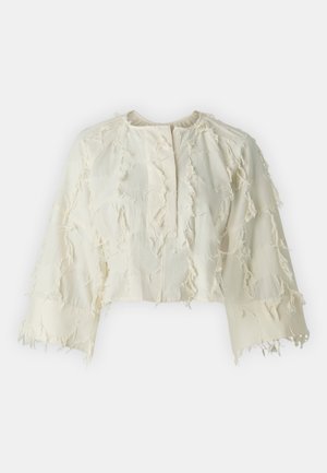 White cropped top made of textured fabric with frayed embellishments. Features a round neckline and wide sleeves, button closure at the front.